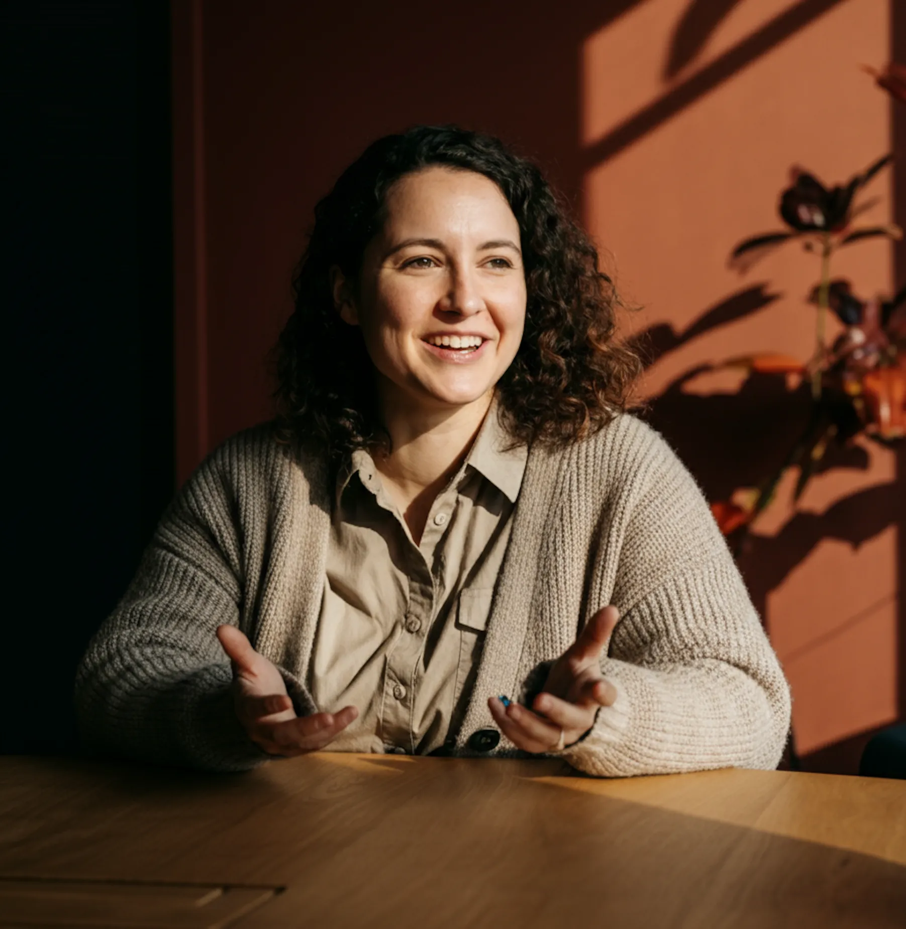 Portrait of a smiling person sitting at a desk, used in the values or about section.